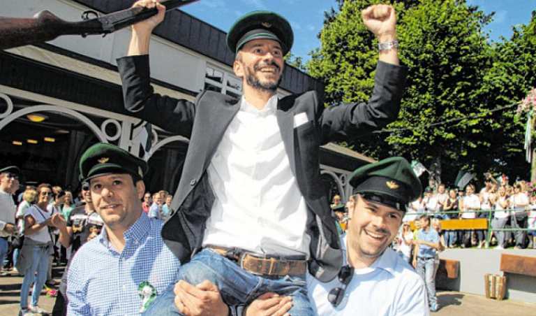 Die beiden Korporalschaftsführer der Zweiten Ralf und Jörg Muckenhaupt tragen Stephan Neuhaus zum Rotweintisch. Foto: Nicole Voss