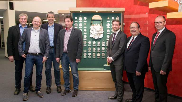 Die neue Vitrine des St. Sebastianus Schützenvereins Olpe e. V. ist ab sofort für Interessierte in der Kundenhalle der Sparkassen-Hauptstelle zugänglich. Die Leutnants Thomas Hengstebeck und Stefan Immekus, Oberleutnant Peter Kliche, Major Peter Liese sowie die Vertreter der Sparkasse Leiter Marketing Mario Grunau und die Sparkassendirektoren Dieter Kohlmeier und Wilhelm Rücker (v. l. n r.) freuen sich, die Königskette mit weiteren 128 Orden auf diese Weise dauerhaft der breiten Öffentlichkeit zu den Geschäftszeiten der Sparkasse zu präsentieren.